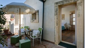 An outdoor patio with a table, chairs, and a large umbrella. - Palazzo del Sale (Syracuse)