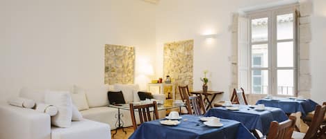 A dining area with tables set for a meal, a sofa, and a stone wall.
