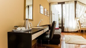 A hotel room with a black desk, a chair, a large mirror, and a window with curtains. - Garden House   & Eastpark Apartments (Munich)