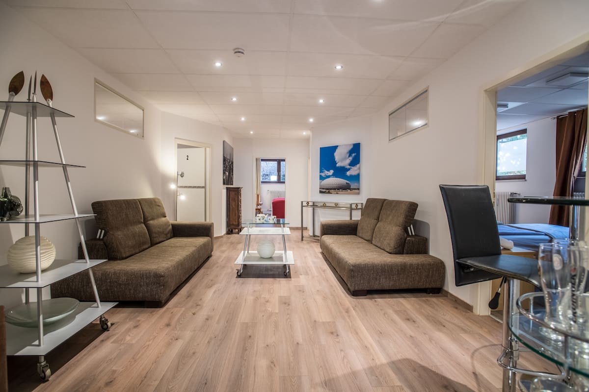 Een moderne woonkamer met twee banken, een salontafel en een glazen wandplank.