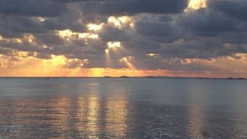 Un atardecer sobre una superficie de agua tranquila con una costa lejana.