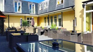 Un patio con mobiliario exterior y una mesa de vidrio.