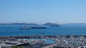 Un puerto deportivo con varias embarcaciones, incluyendo veleros y un gran barco, amarradas en aguas tranquilas.