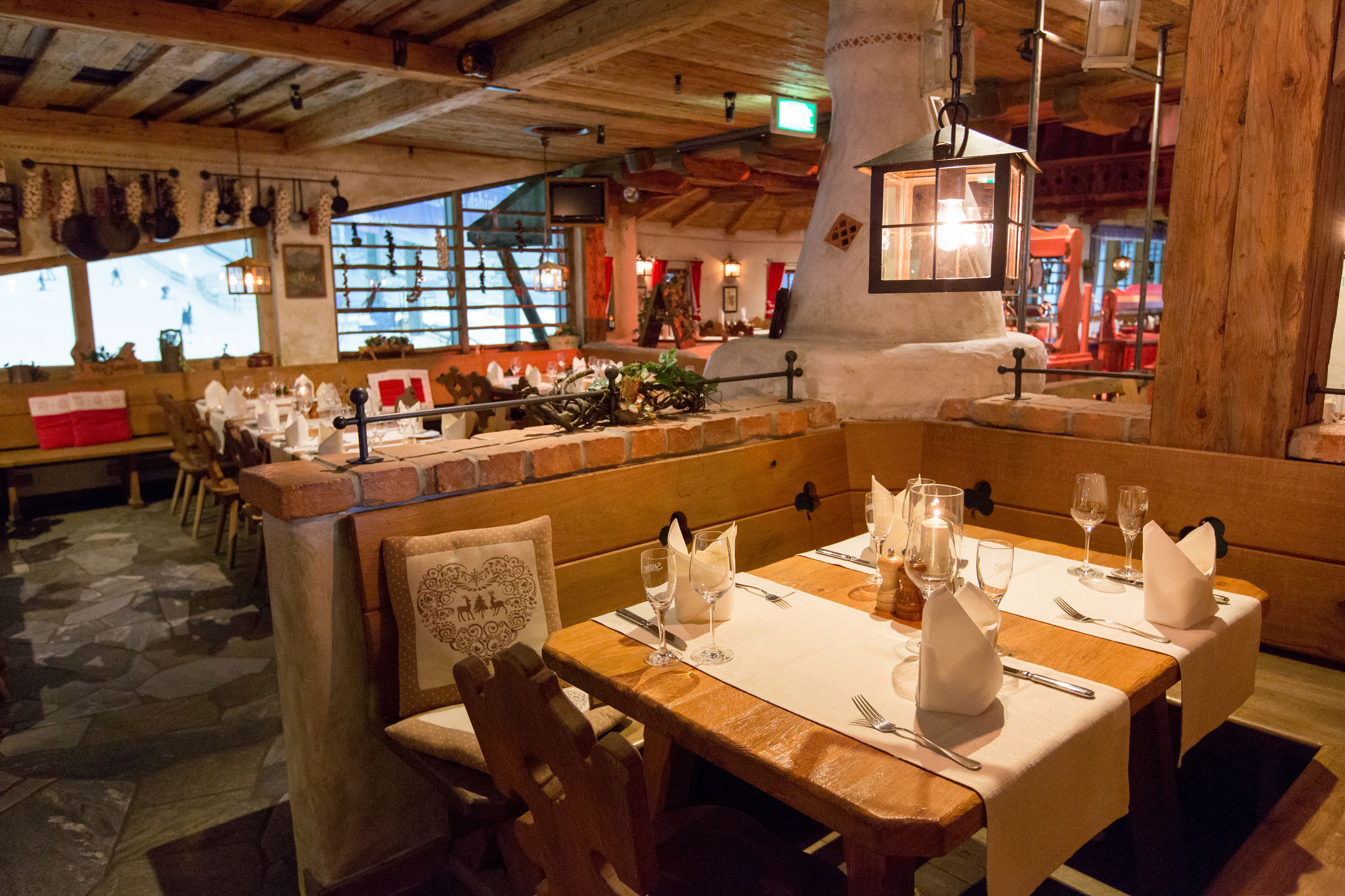 Un restaurante con mesas de madera dispuestas para comer, suelo de piedra y una decoración rústica.