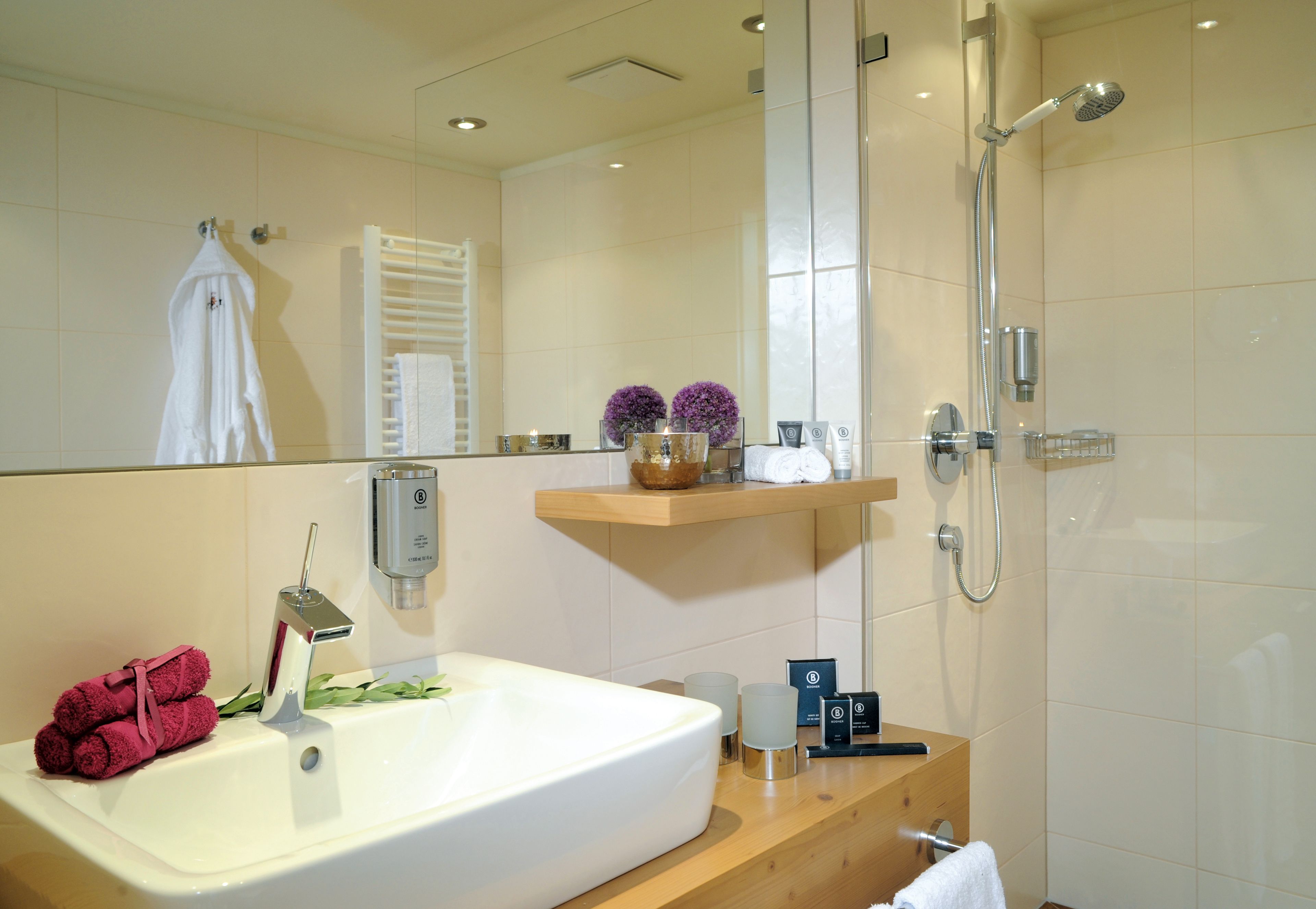 Un baño moderno con un lavamanos grande, un espejo, ducha y tocador de madera.