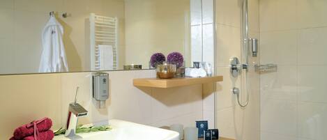 Un baño moderno con un lavamanos grande, un espejo, ducha y tocador de madera.