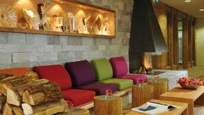 Un vestíbulo acogedor con una pared de piedra, sofás coloridos, una chimenea y una mesa de centro de madera con un frutero.