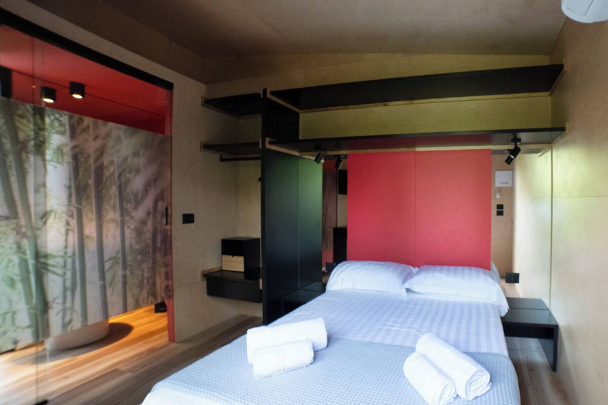 Ett hotellrum med en säng, ett nattduksbord och en vägg med en röd panel.