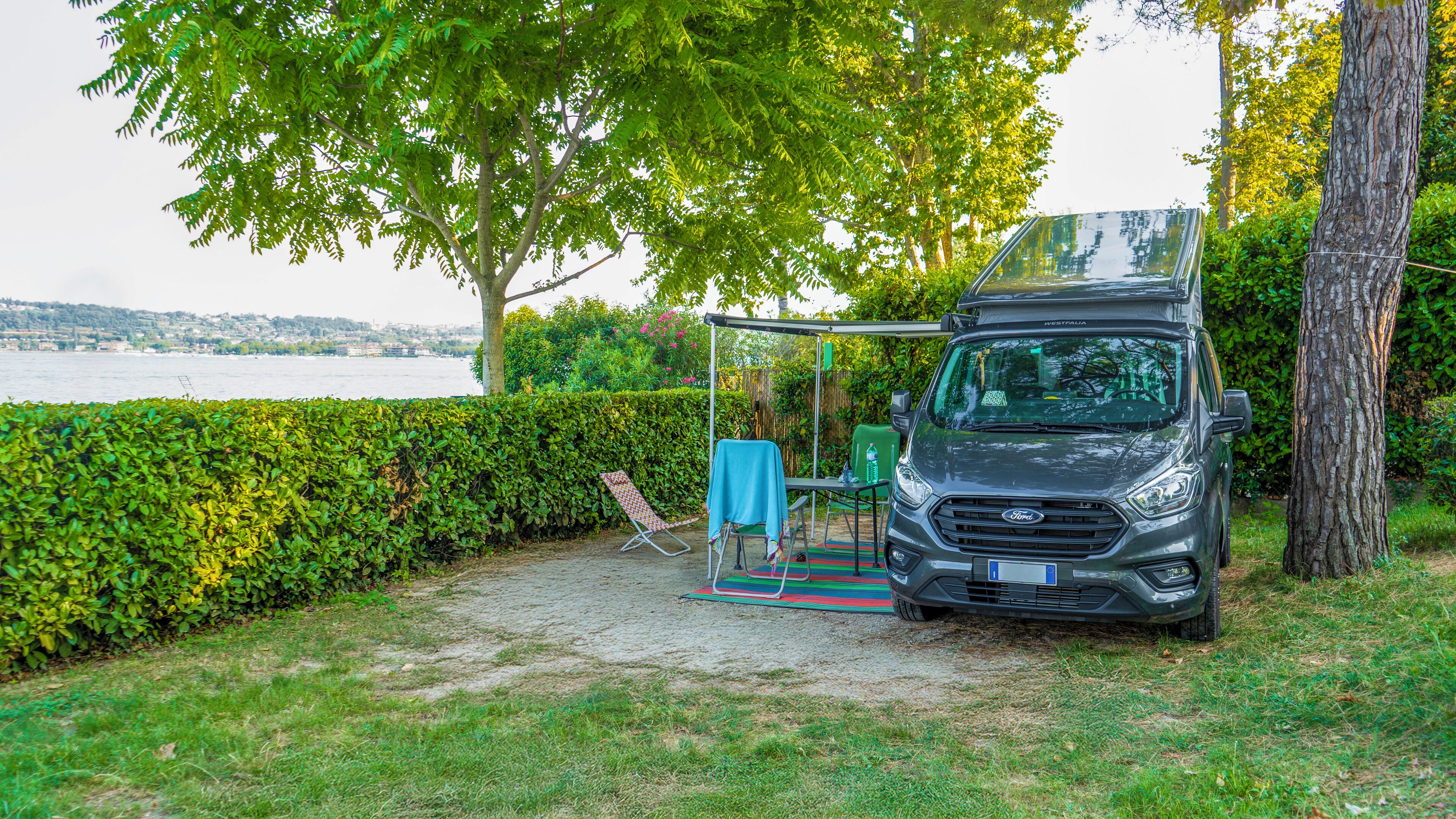 A campsite with a tent, a table with chairs, and a view of a body of water.