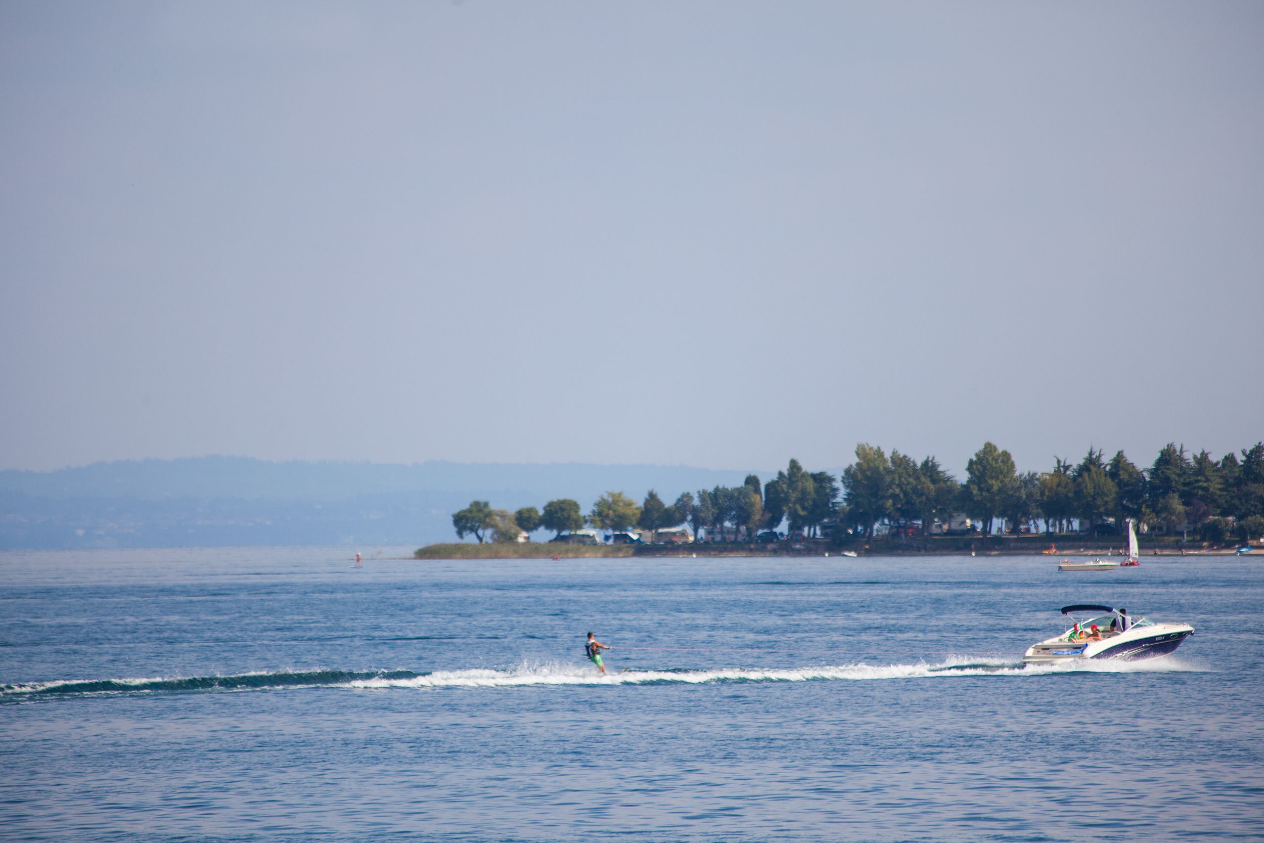 A body of water with a person wakeboarding and a boat in the distance.