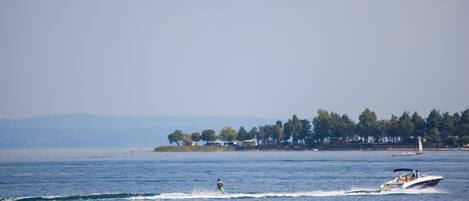 A body of water with a person wakeboarding and a boat in the distance.