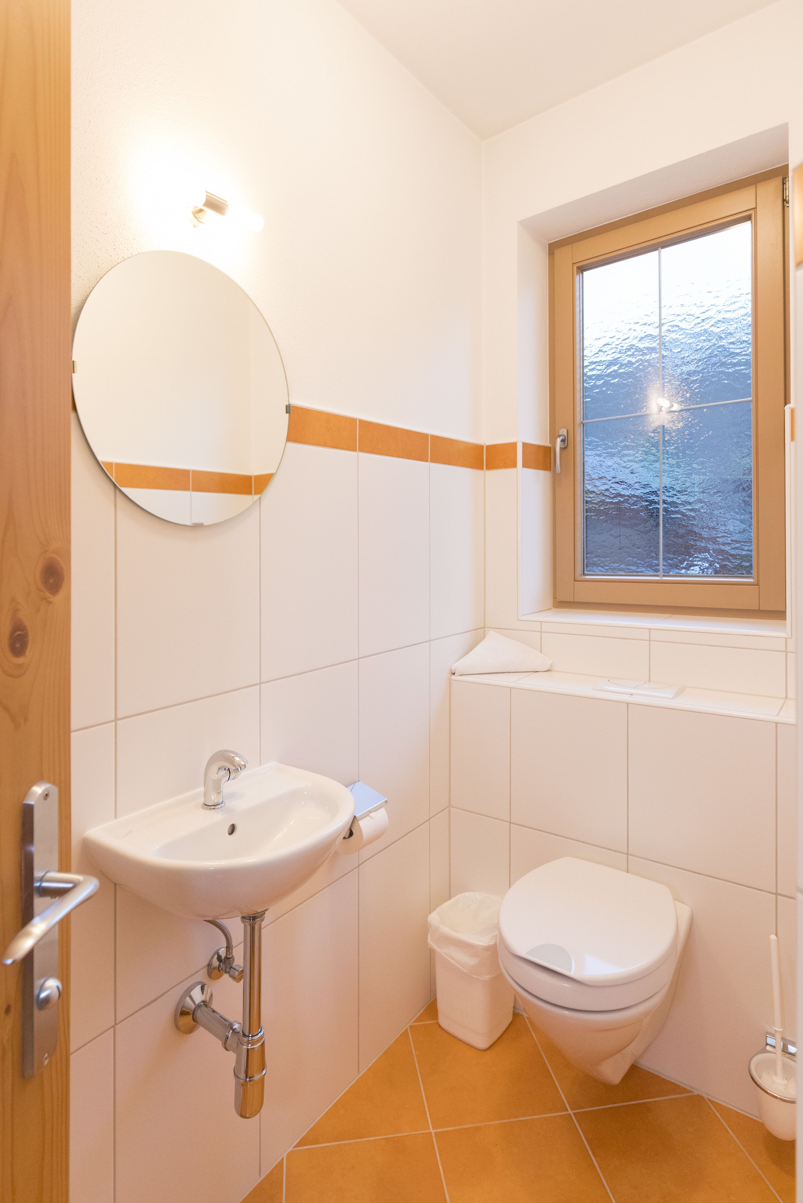 A bathroom with a sink, toilet, and a window with a view of the outdoors.