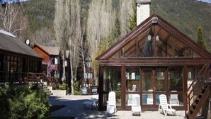 A lodge with a wooden structure, outdoor seating, and a view of a mountainous landscape. - Rincon de los Andes Resort (San Martín de los Andes)