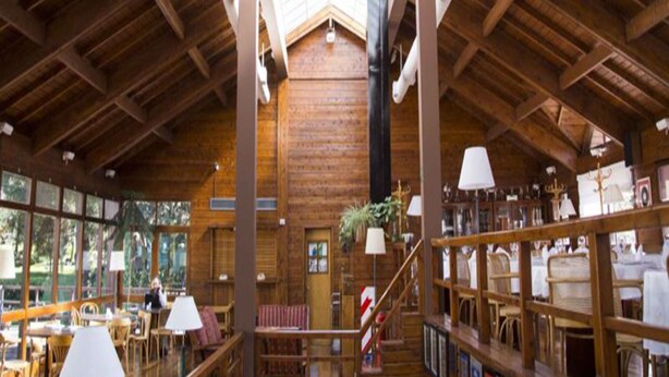 A spacious interior with high ceilings, wooden beams, and a central staircase. - Rincon de los Andes Resort (San Martín de los Andes)
