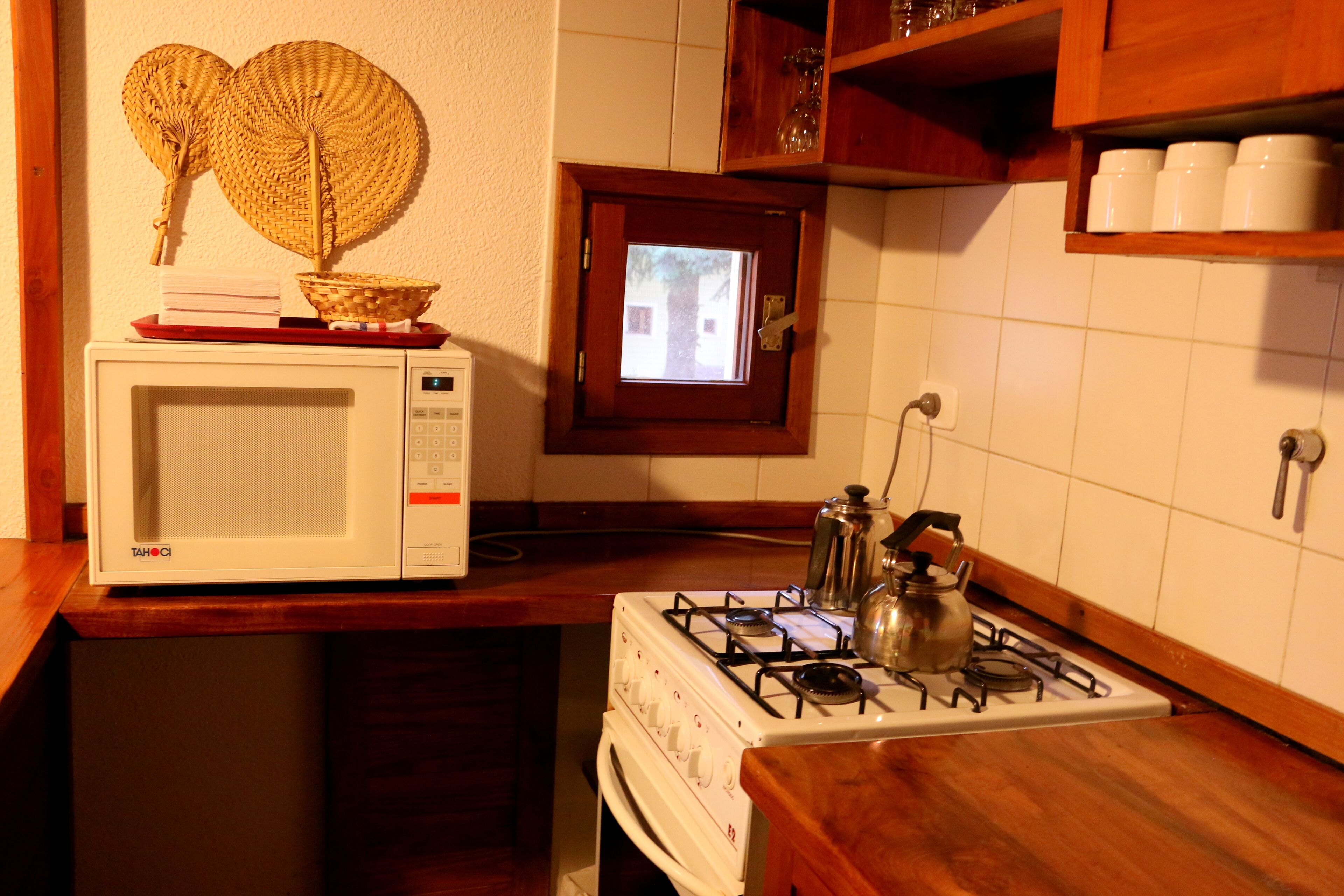 Una cocina con microondas, estufa y un ventanal.