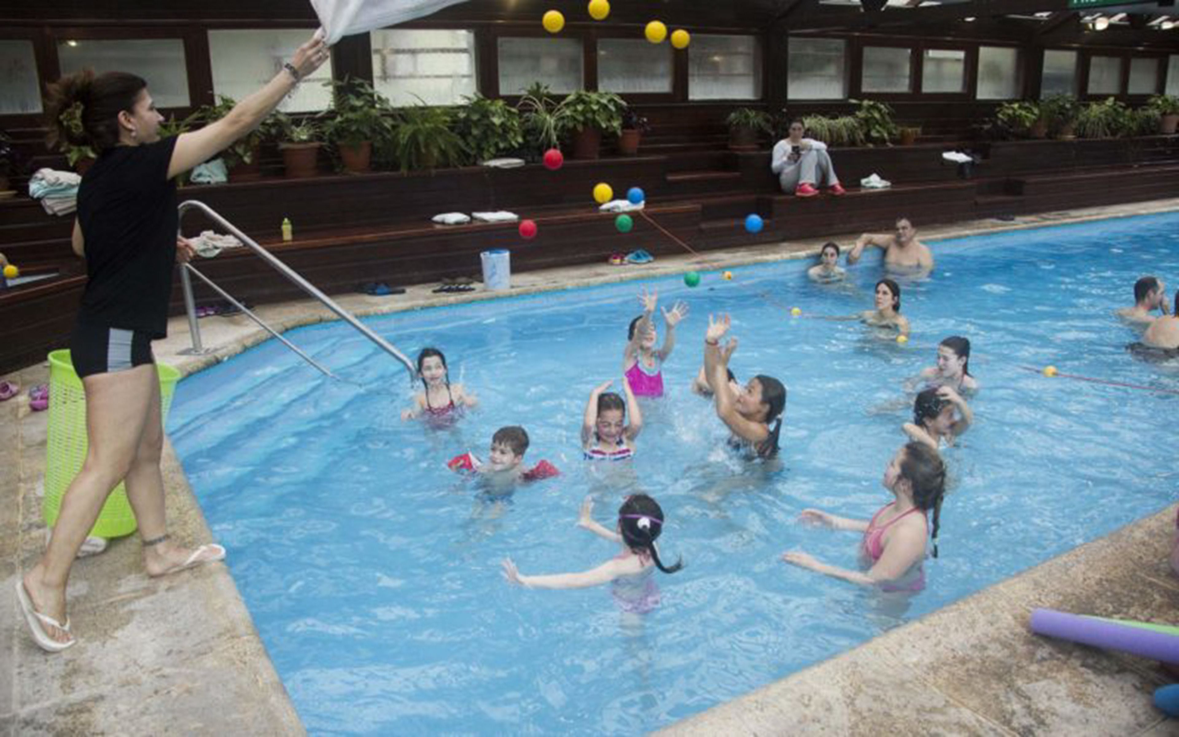 Piscina com pessoas brincando e salva-vidas.