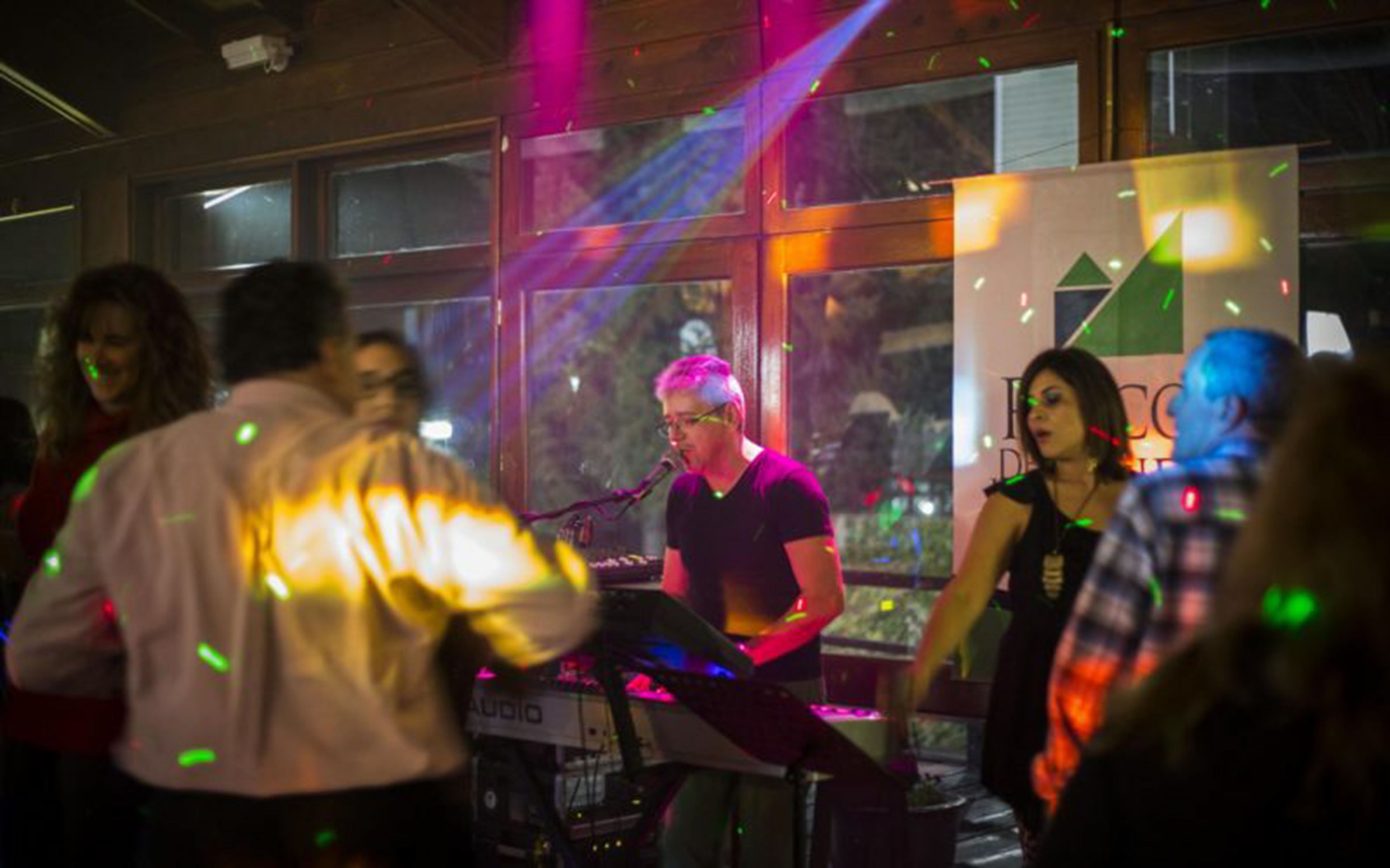 A group of people at an indoor event with a stage and a banner in the background.