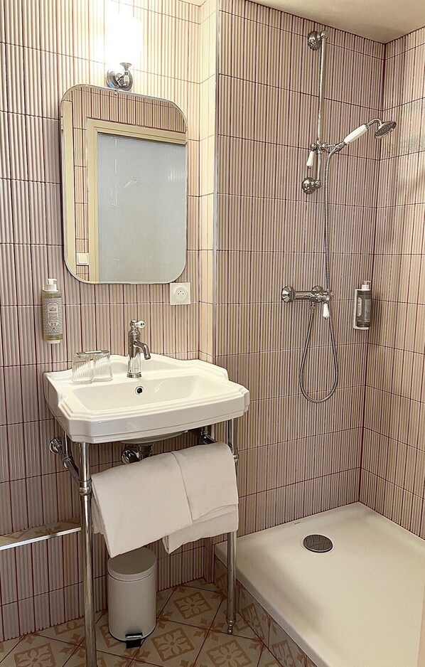 A bathroom with a sink, mirror, towel rack, shower, and toilet.