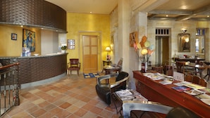 Un hall d’hôtel comprenant un comptoir d’accueil, un espace salon et un espace repas.
