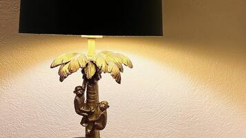 En messingbordlampe med skærm i sort og en dekorativ base der forestiller en palme.