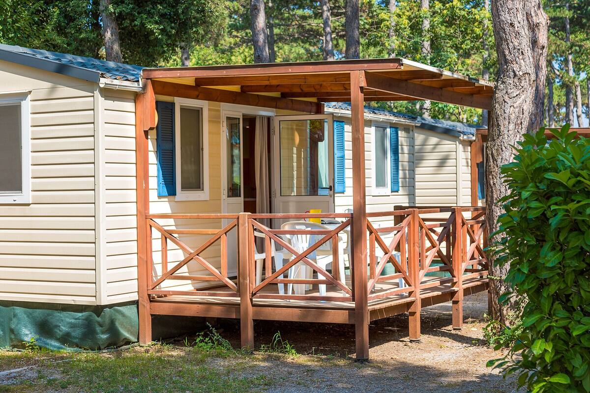 A mobile home with a wooden deck and a covered porch.