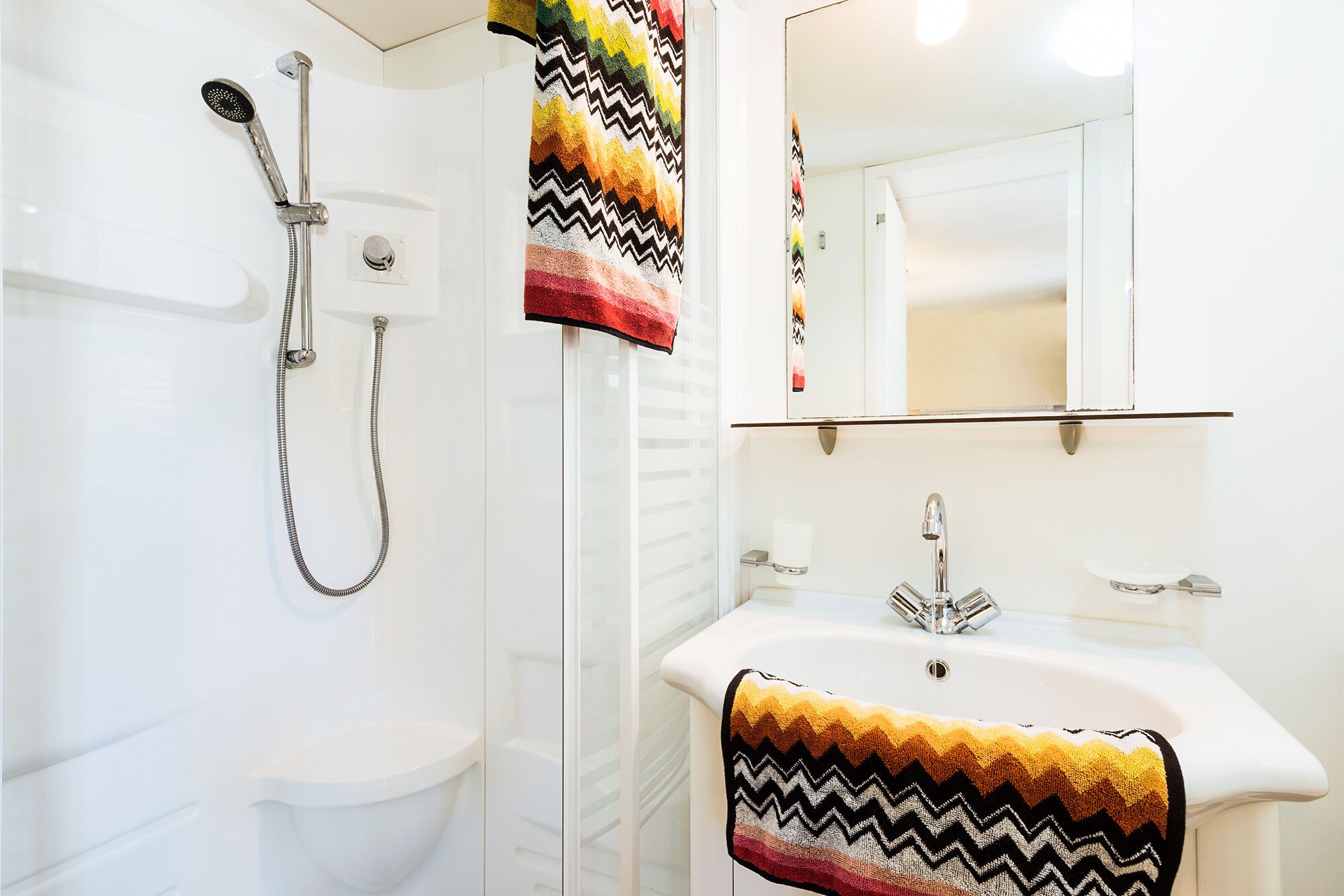 Un baño con ducha, inodoro, lavabo y espejo.
