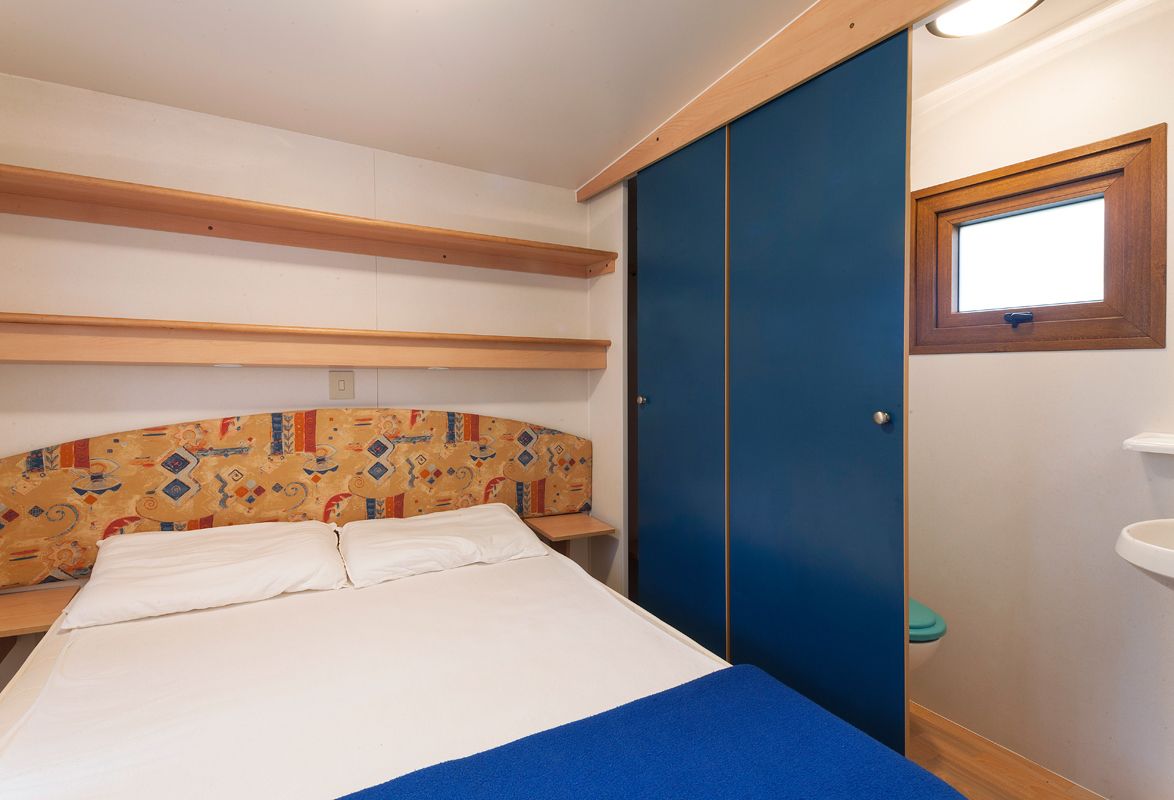 Un dormitorio con cama, armario, ventana y lavamanos.