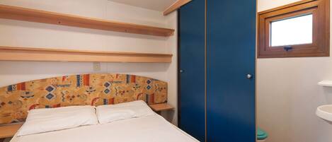 Un dormitorio con cama, armario, ventana y lavamanos.