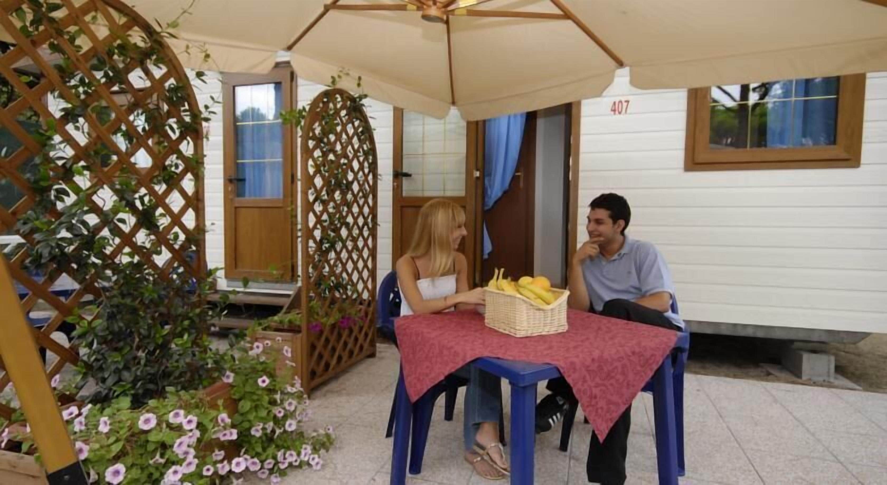 Eine Terrasse im Freien mit Tisch und Stühlen, einer Holzveranda und einem Haus im Hintergrund.