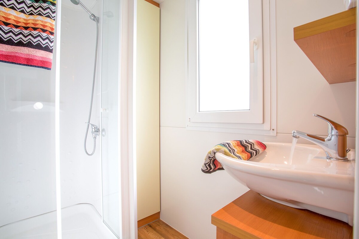 A bathroom with a shower, a sink, and a window.