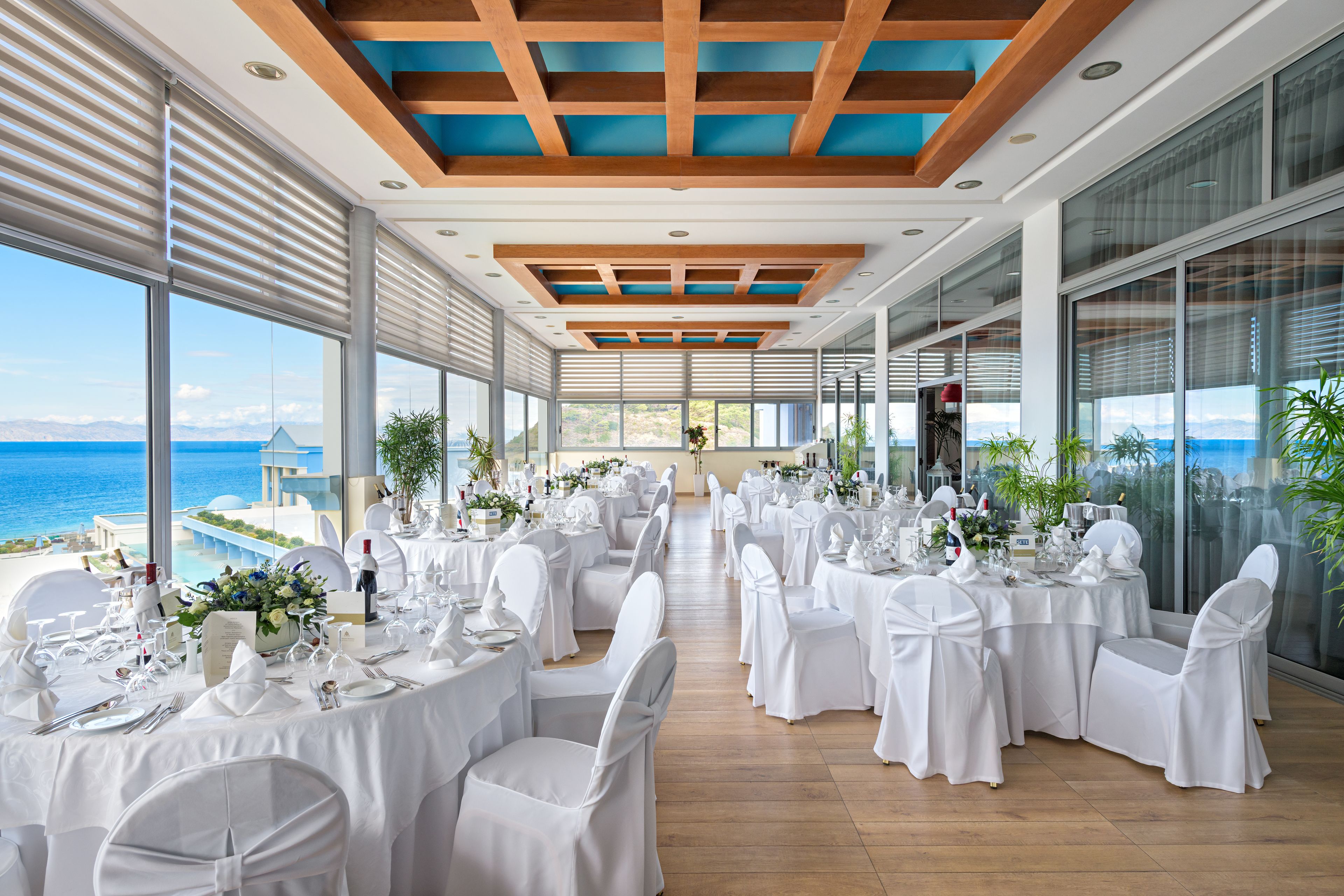 A banquet hall with tables set for a formal event, overlooking a scenic ocean view.
