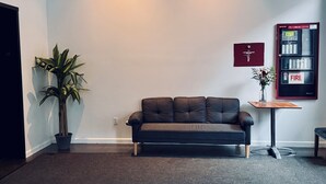 Een moderne woonkamer met een donker leren bank, een potplant en een haardregeling aan de muur.