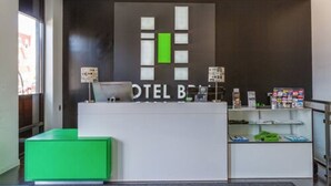 Een hotel receptie met een modern design, een zithoek in groentinten en een overzicht van faciliteiten.