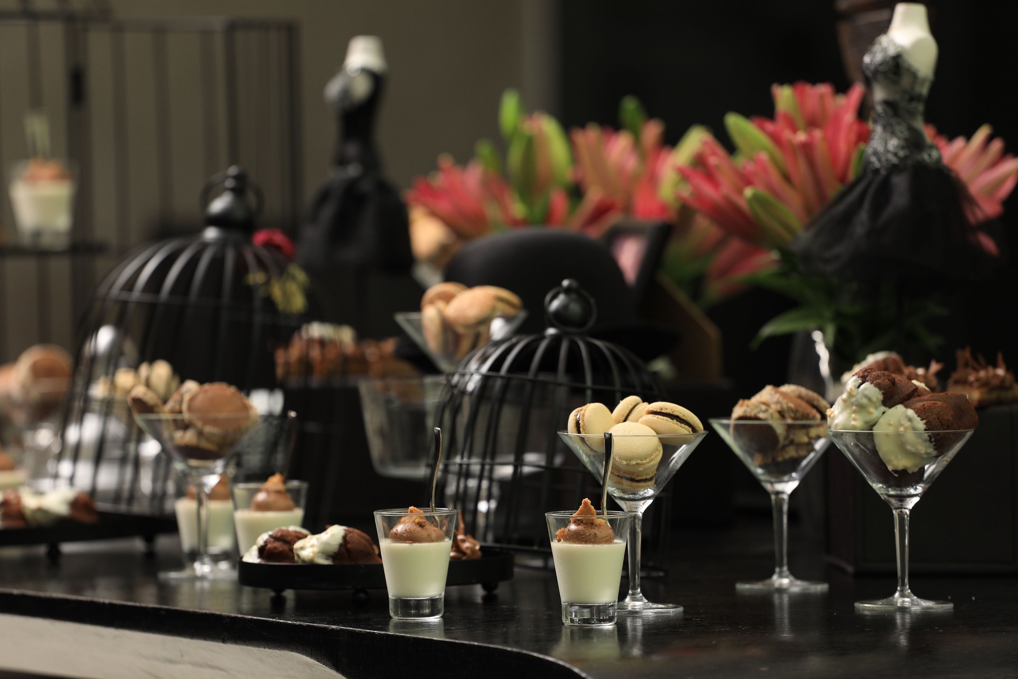 Una barra de postres con diversos pasteles y dulces en vasos de martini.