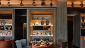 Un interior moderno con zona de comedor, estanterías y máscaras decorativas.