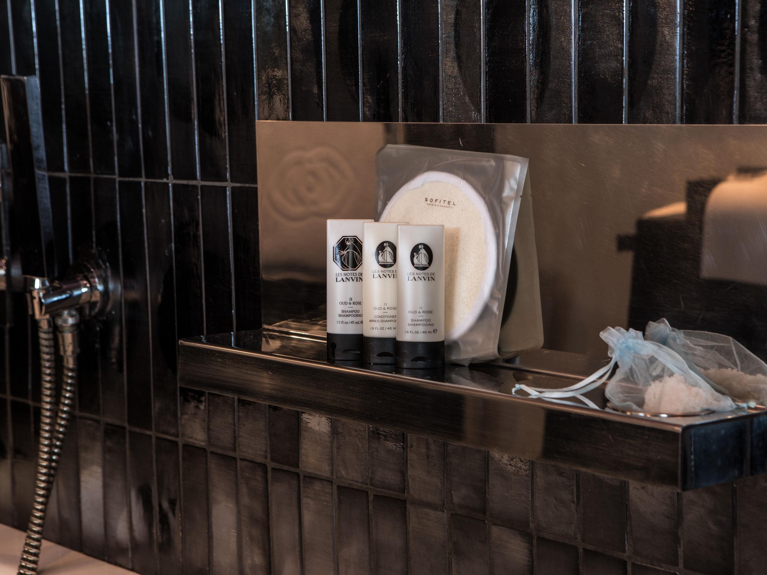 Un meuble-lavabo de salle de bain avec un miroir, un porte-serviettes et des articles de toilette, notamment un flacon de shampoing et un flacon d’après-shampoing.
