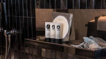 Un meuble-lavabo de salle de bain avec un miroir, un porte-serviettes et des articles de toilette, notamment un flacon de shampoing et un flacon d’après-shampoing.