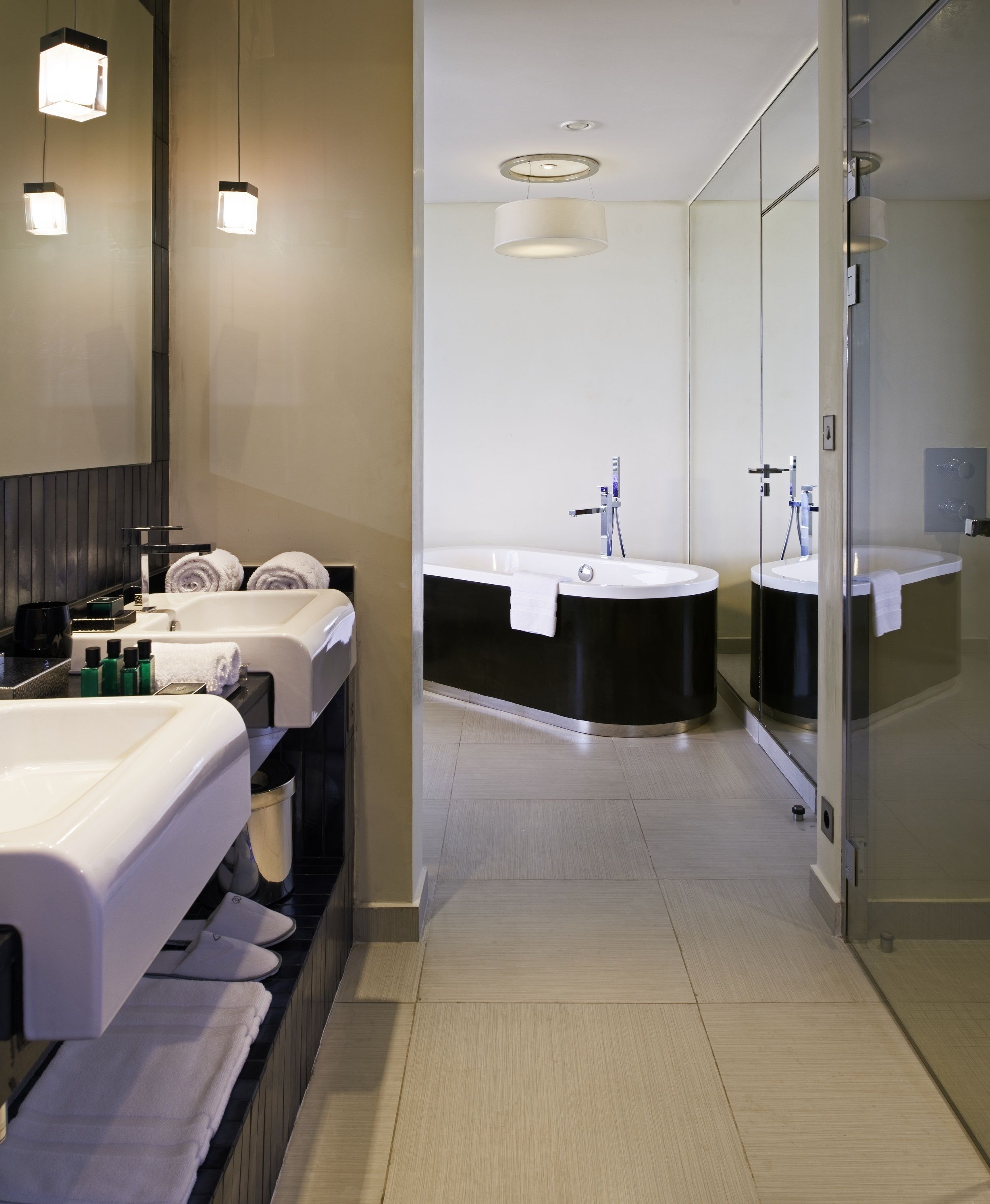Une salle de bain moderne avec un meuble-lavabo, deux vasques, une baignoire et une douche.