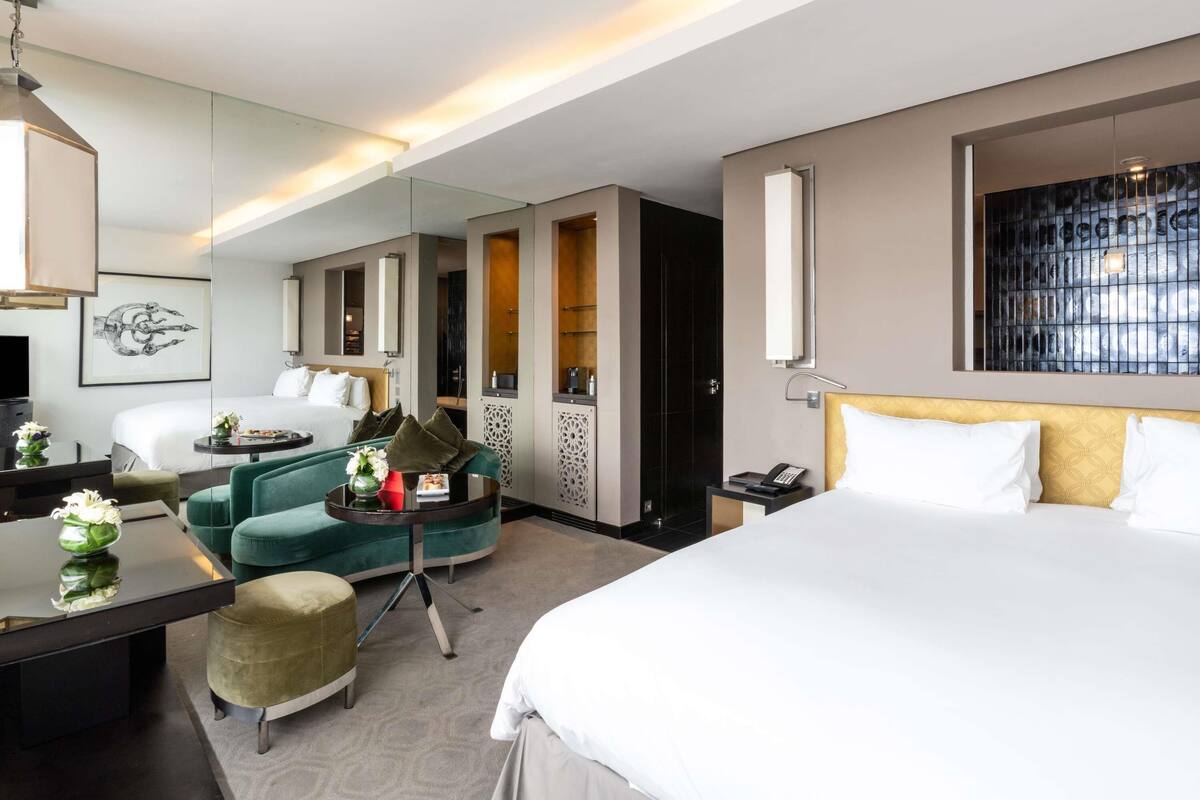 Una habitación de hotel con cama, escritorio con silla, sofá, espejo y televisor.