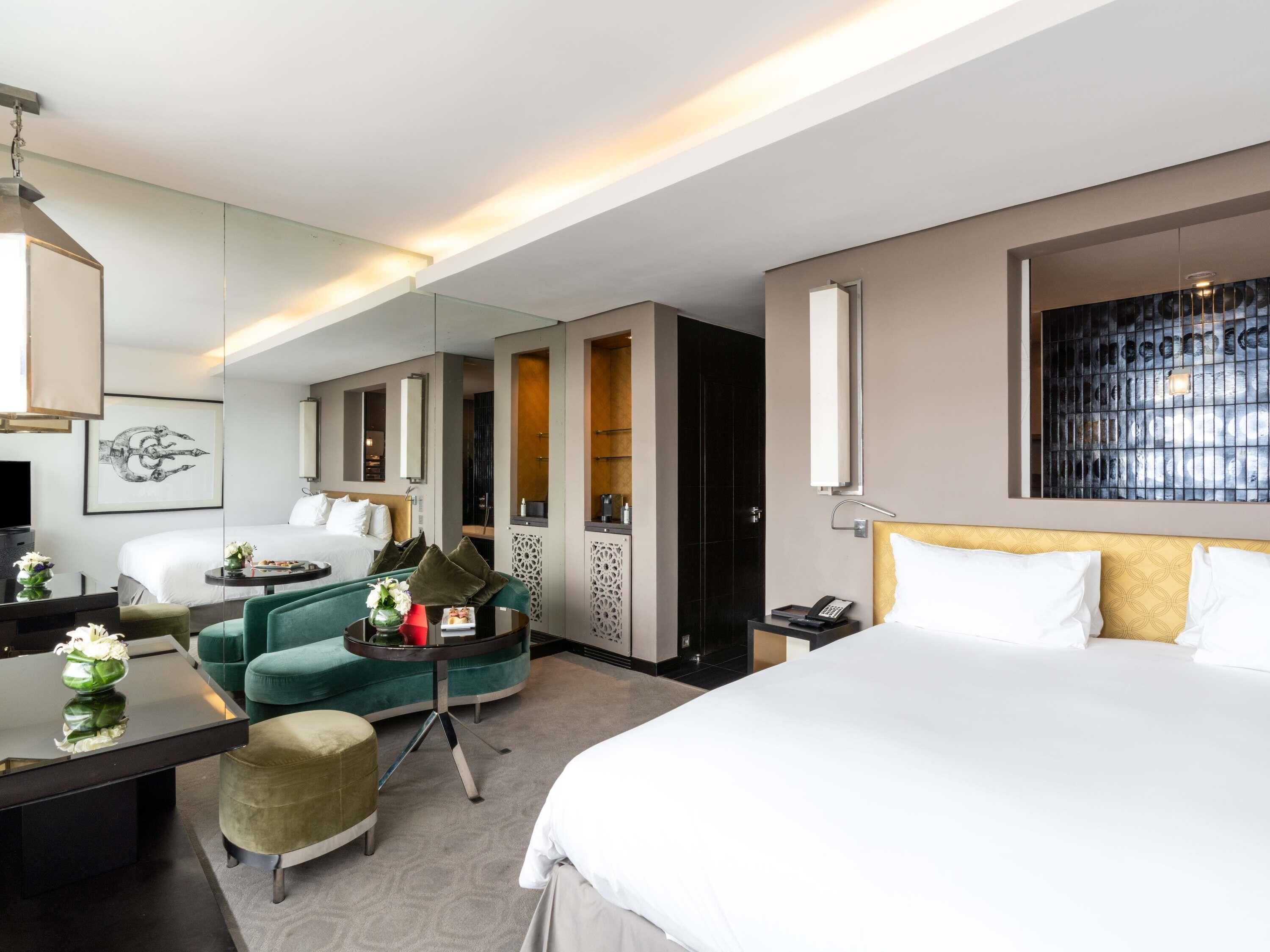 A hotel room with a bed, a desk with a chair, a sofa, a mirror, and a TV.