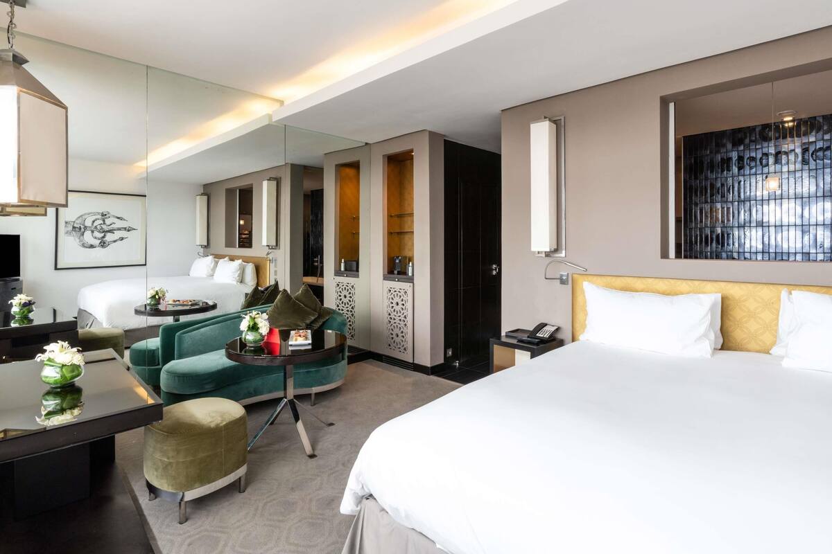 Habitación de hotel con cama, escritorio, silla, espejo y televisor.