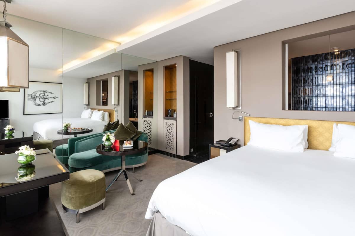 A hotel room with a bed, a desk, a chair, a mirror, and a TV.