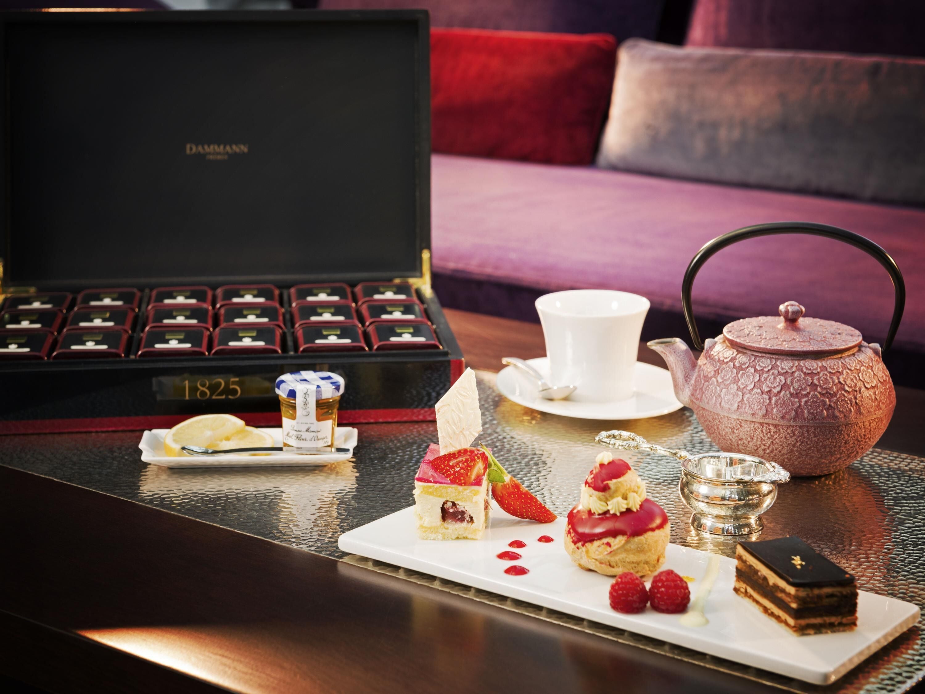 Un entorno lujoso con un juego de té, una selección de postres y una vitrina de joyería.