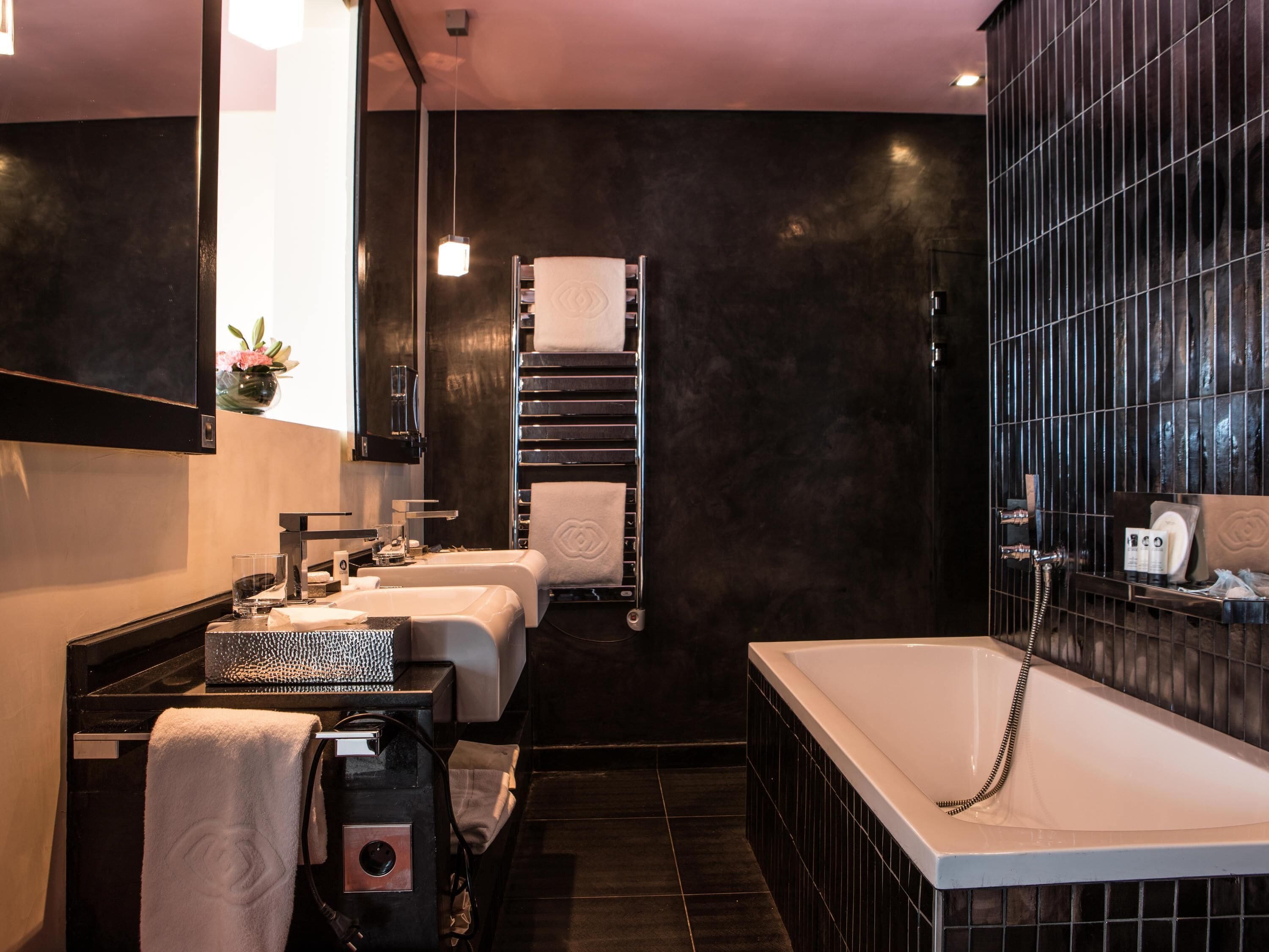 A modern bathroom with a large bathtub, a double sink, and a towel rack.