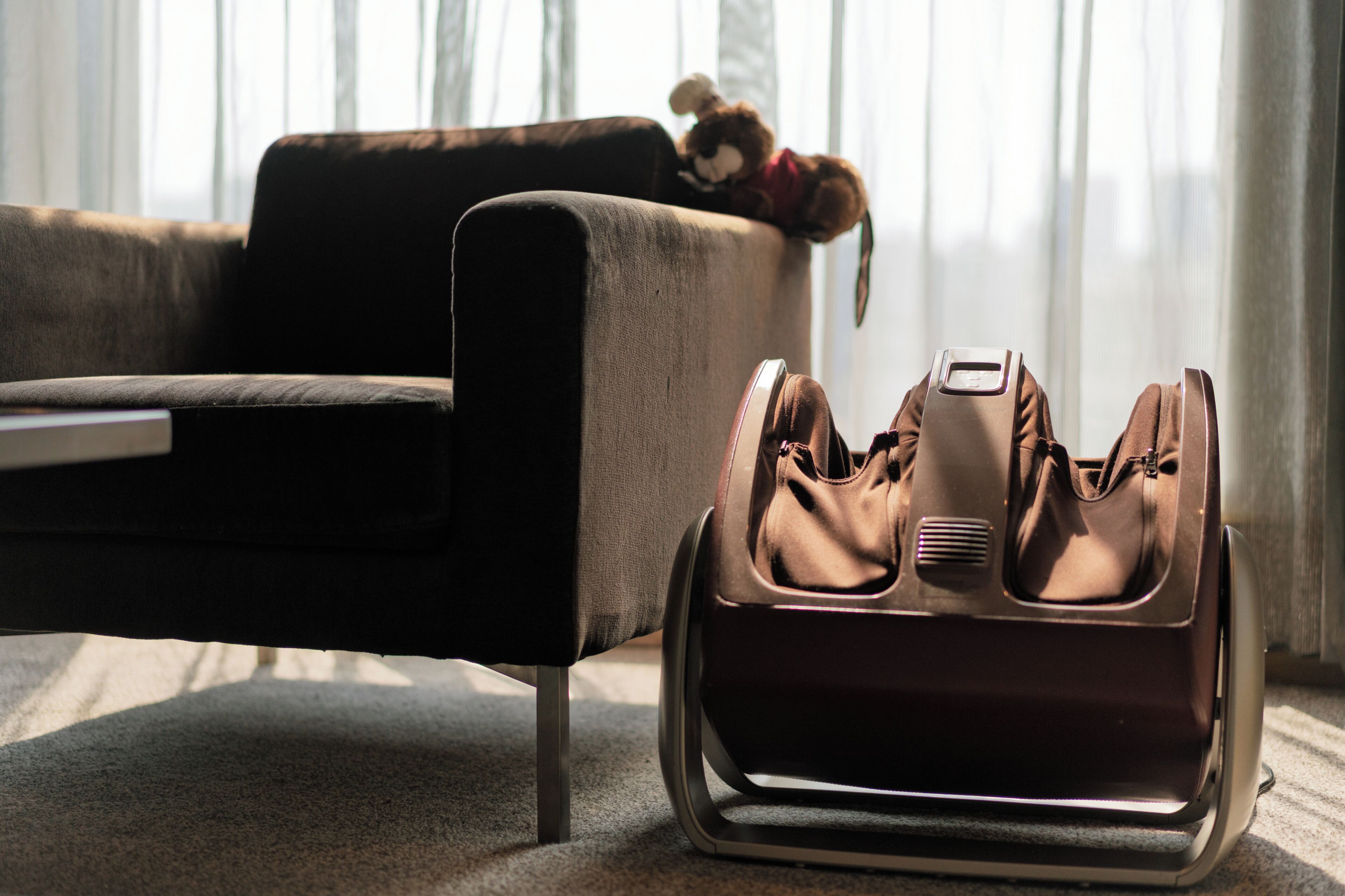 A room with a sofa, a pair of shoes, and a suitcase.
