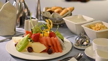 A breakfast setting with a plate of fruit, bread, and a cup of coffee.