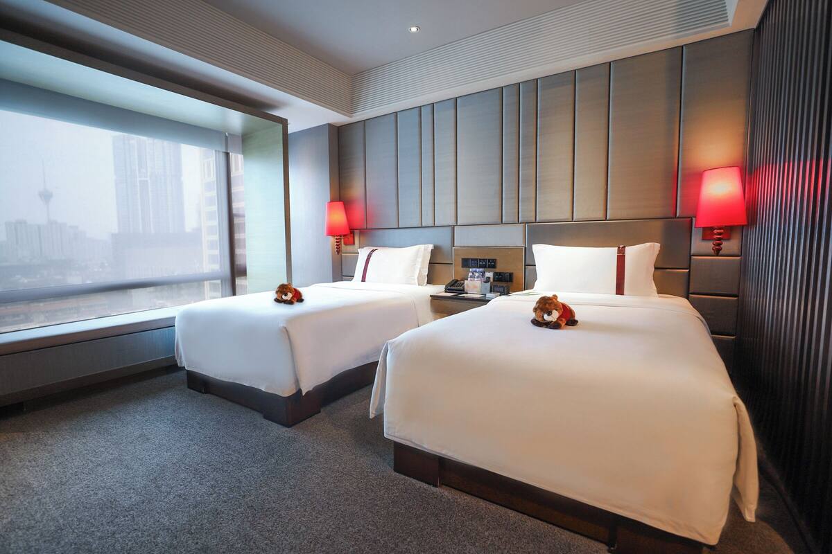 Une chambre d’hôtel avec deux lits, une vue sur la ville et un design moderne.