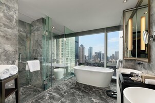 Un baño moderno con ducha acristalada, una bañera independiente y un tocador con espejo.