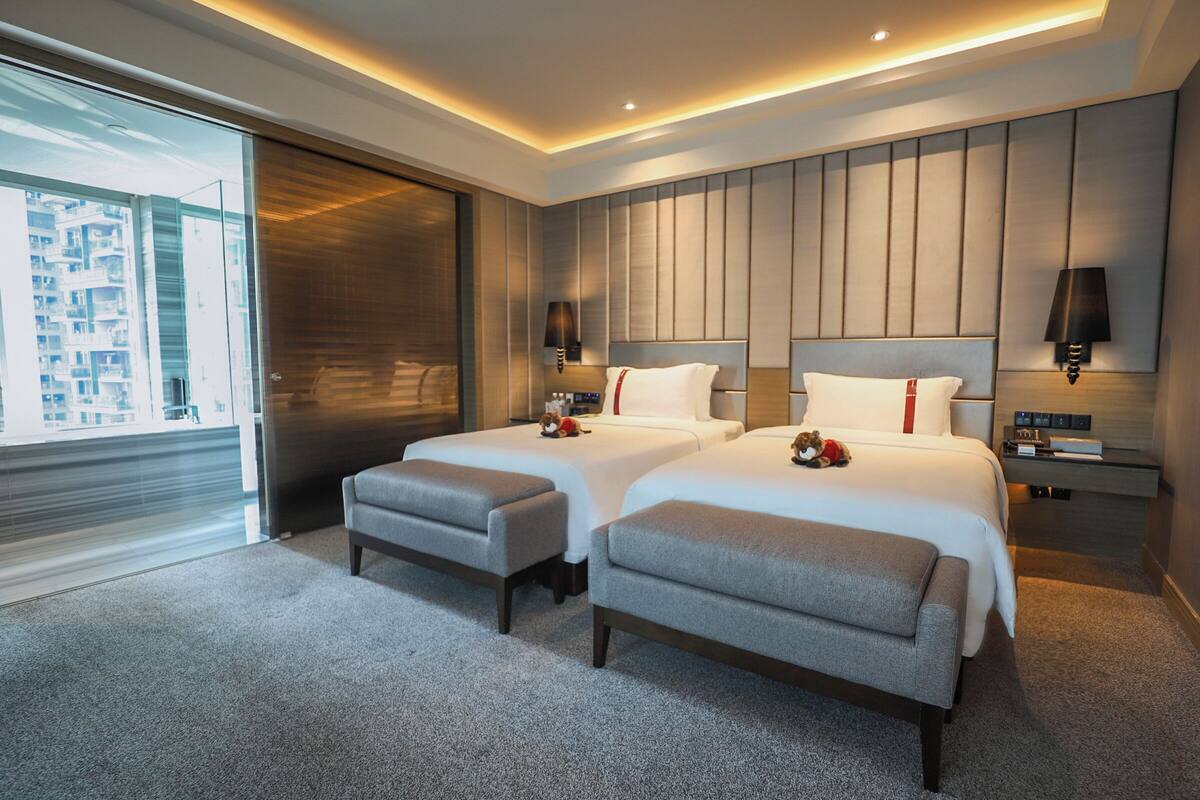 Une chambre d’hôtel moderne avec deux lits, une grande fenêtre et une vue sur la ville.