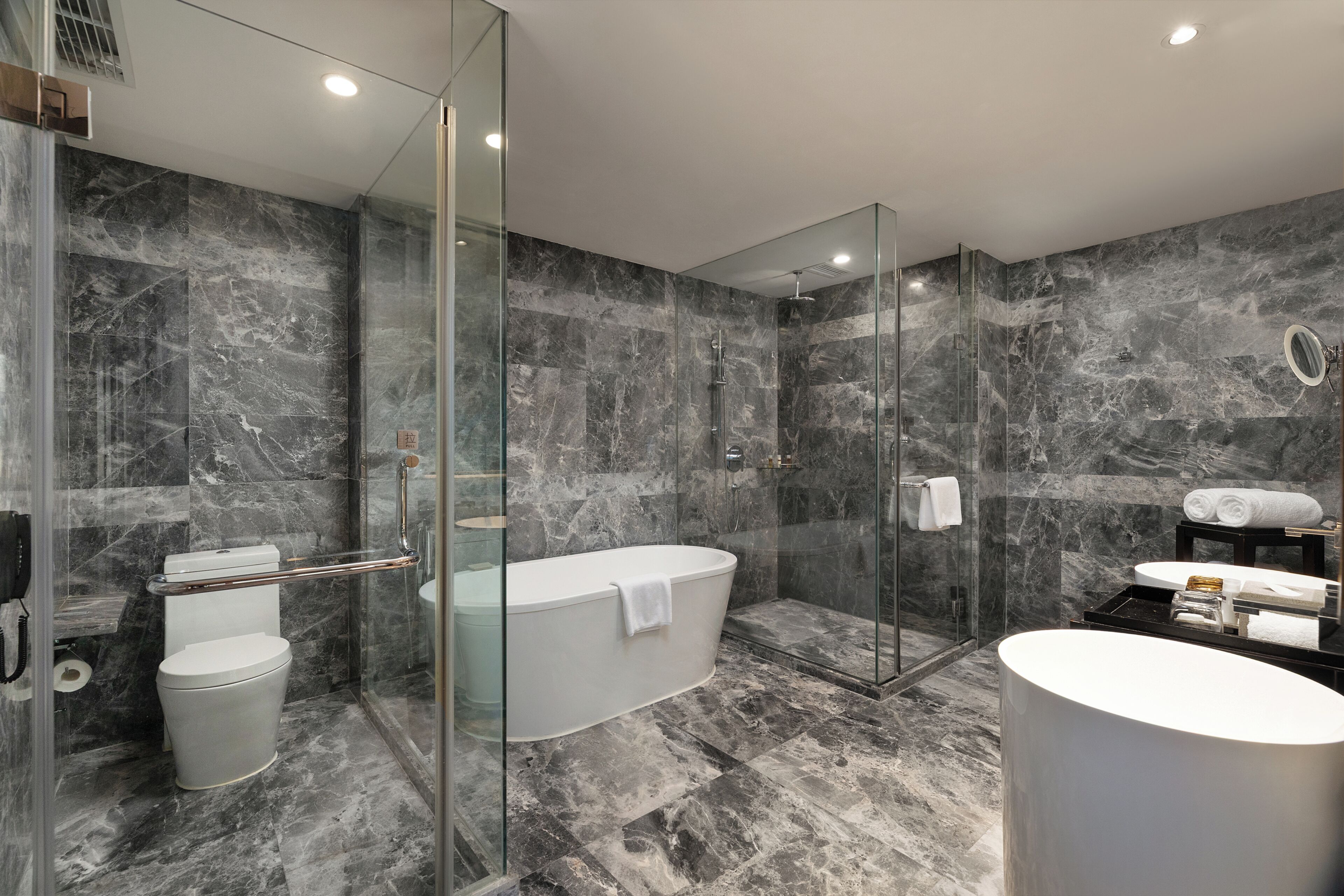 A modern bathroom with a glass-enclosed shower, a freestanding bathtub, and a round sink.